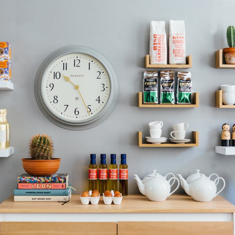 Minimalist kitchen wall with clock and wooden shelves