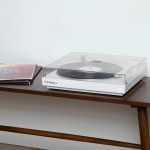 White turntable with vinyl record on wooden table
