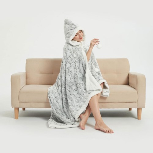 Woman wearing hooded blanket sitting on beige sofa