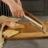 Hand slicing baguette with curved serrated bread knife