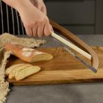 Hand slicing baguette with curved serrated bread knife