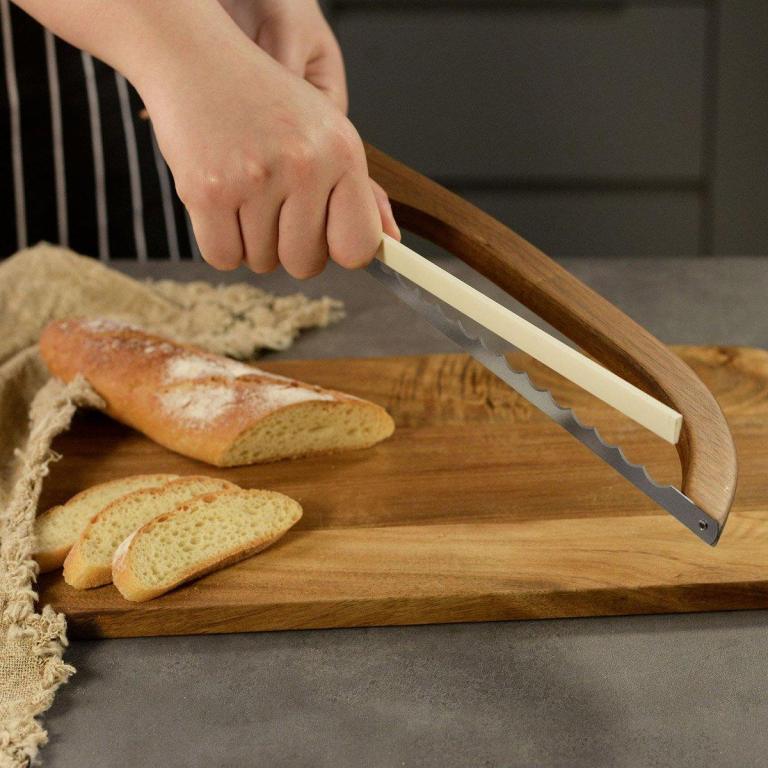 Hand slicing baguette with curved serrated bread knife