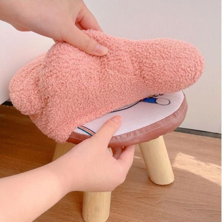 Pink fluffy stool cover on wooden stool
