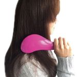 Person brushing long brown hair with pink brush