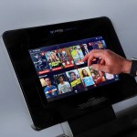 Hand selecting TV show on treadmill touchscreen