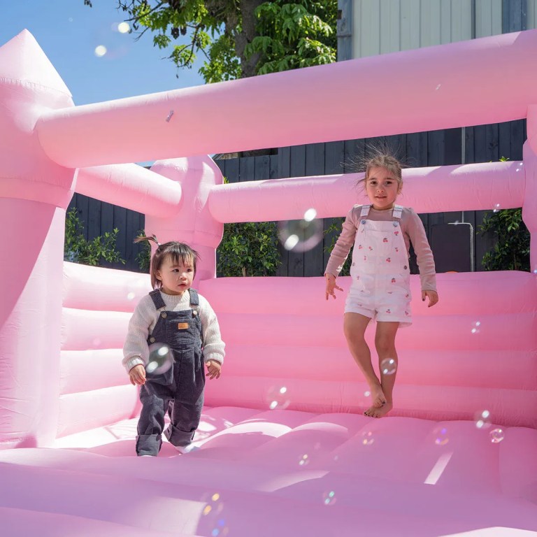 Two children playing in pink bouncy castle