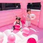 Two toddlers playing with balloons in pink castle