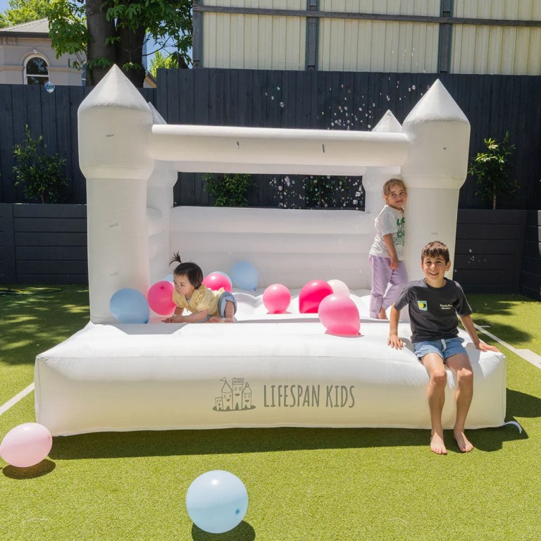 Children playing in white backyard jumping castle