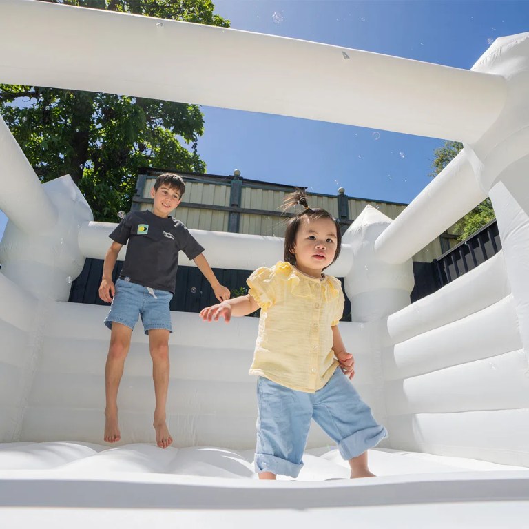 Two children playing in white bouncy castle