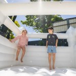 Two children playing in backyard bouncy castle