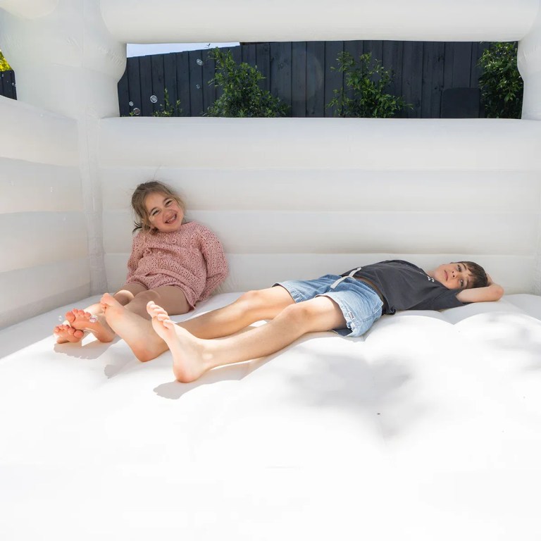 Two children relaxing inside white jumping castle