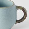 Close-up of textured ceramic mug with rustic handle