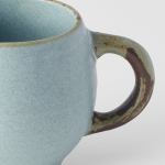 Close-up of textured ceramic mug with rustic handle