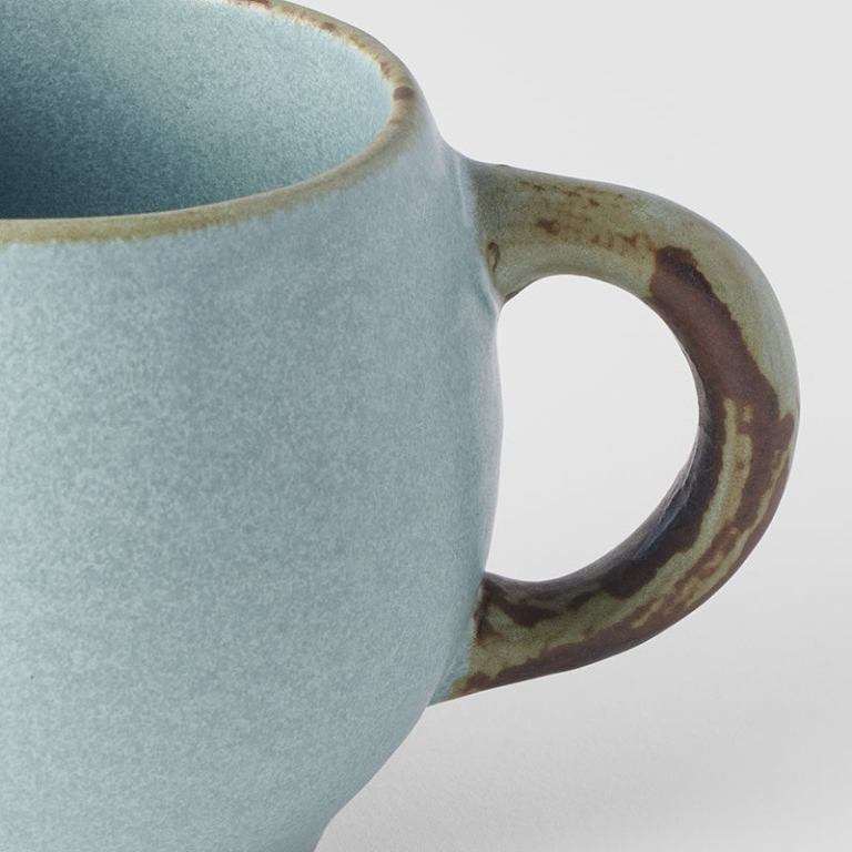 Close-up of textured ceramic mug with rustic handle