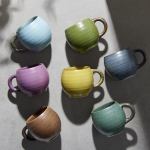 Seven colourful ceramic mugs on neutral background