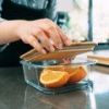 Person storing sliced oranges in glass container