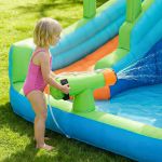Child spraying water on inflatable backyard slide