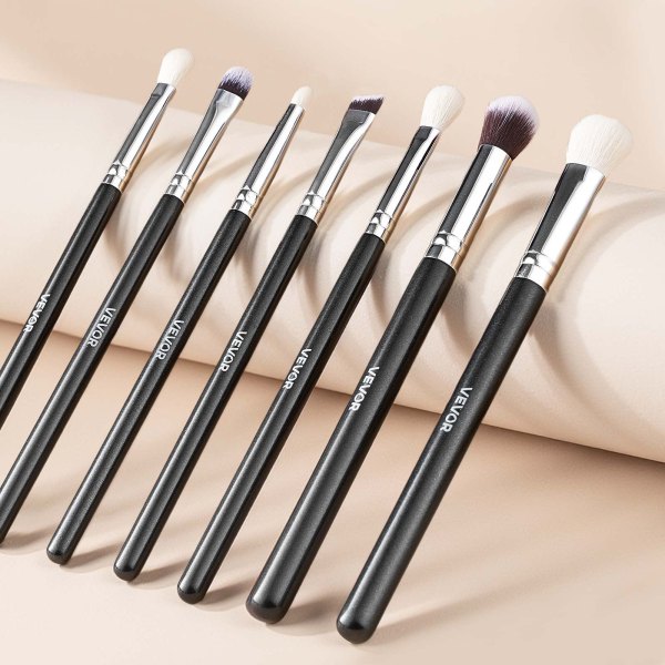 Set of black-handled makeup brushes on beige background