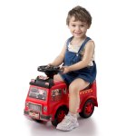 Smiling child riding red toy fire truck