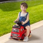 Smiling child riding red toy fire truck