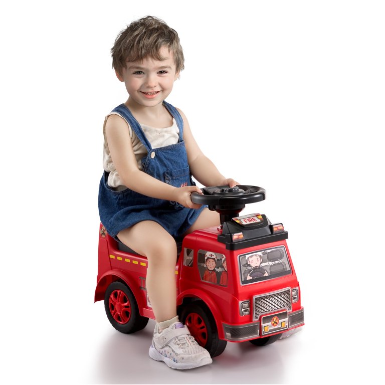 Smiling child riding red toy fire truck