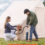 Couple inflating camping tent with hand pump