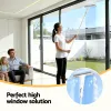 Woman cleaning high window with long-handled squeegee