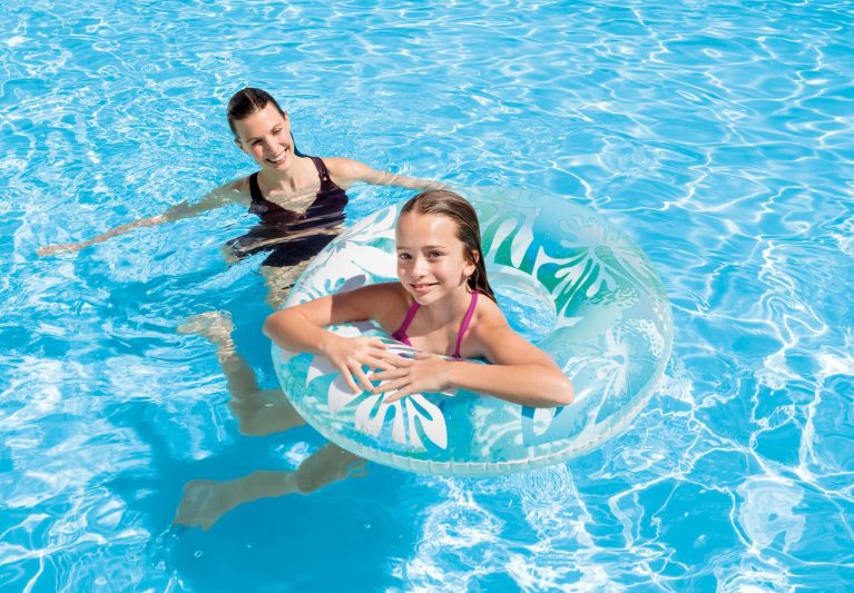 Woman and girl enjoying pool with inflatable ring