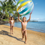 Children playing with giant beach ball on tropical beach