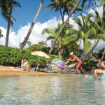Family playing with beach ball on tropical shore