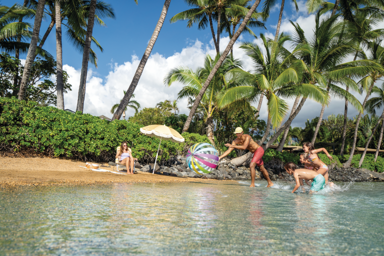 Family playing with beach ball on tropical shore