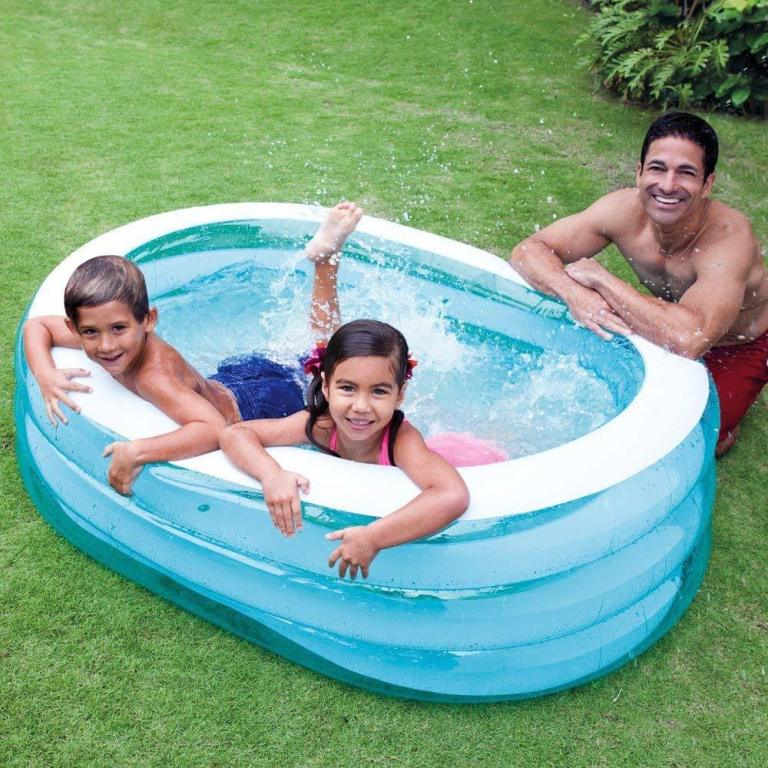Father and two children in backyard inflatable pool