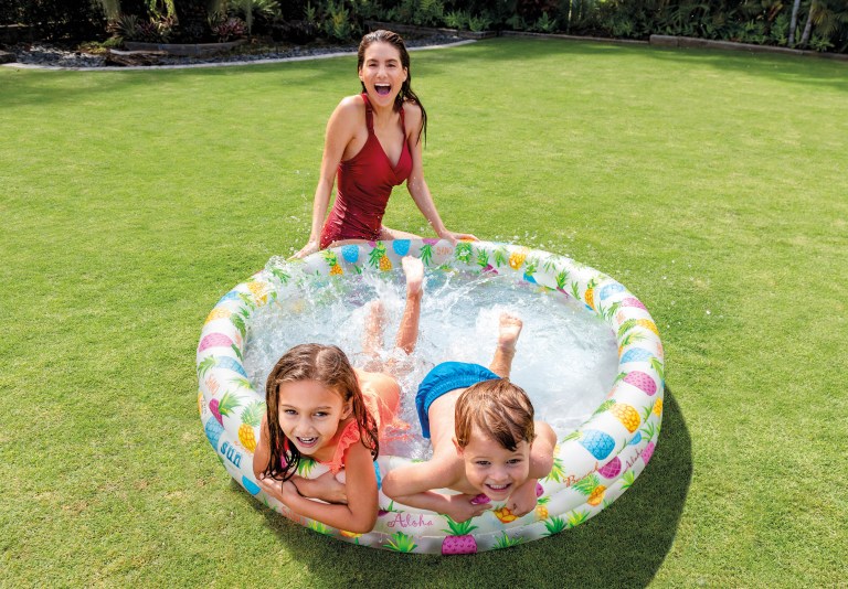 Woman and children splashing in backyard inflatable pool
