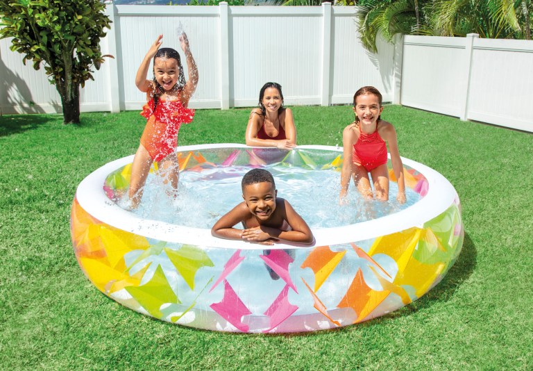 Family splashing in inflatable pool in backyard