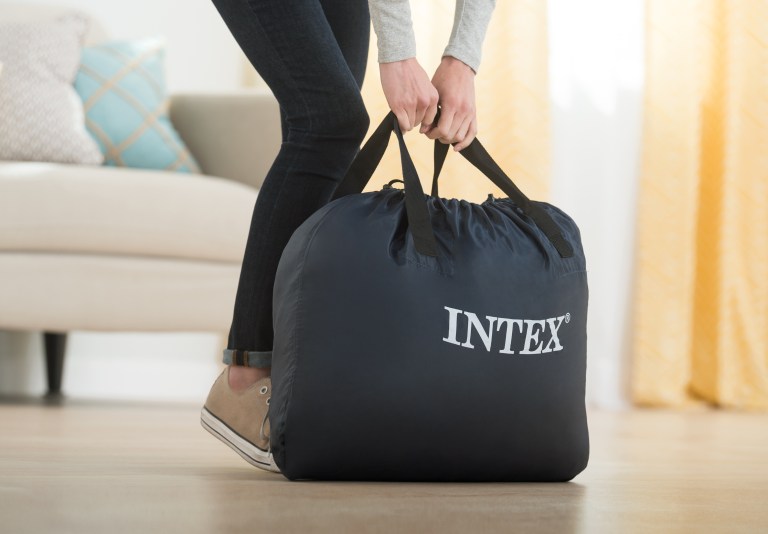Person lifting navy INTEX carry bag indoors