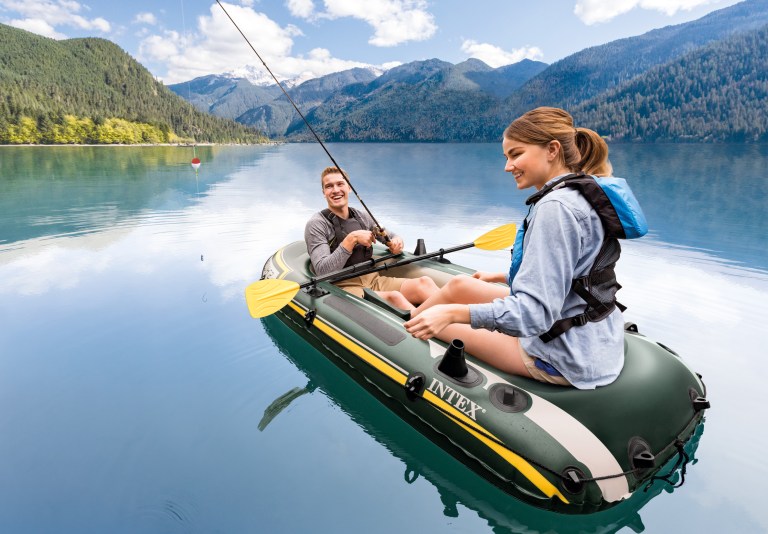 Couple fishing from inflatable boat on mountain lake