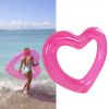 Woman carrying pink heart float at beach
