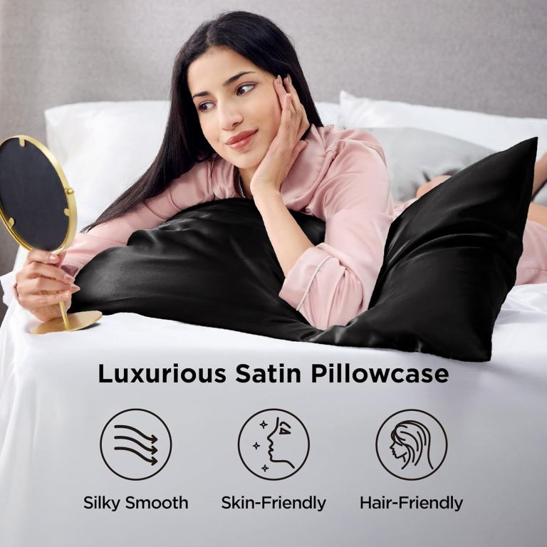 Woman relaxing on black satin pillowcase holding mirror