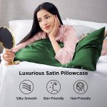 Woman relaxing on green satin pillowcase holding mirror