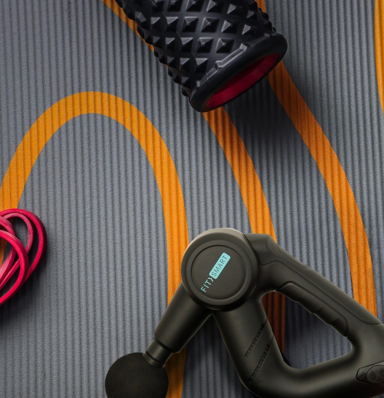 Massage gun and foam roller on exercise mat