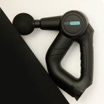 Black handheld massage gun with round foam head