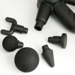 Black massage gun with interchangeable attachment heads