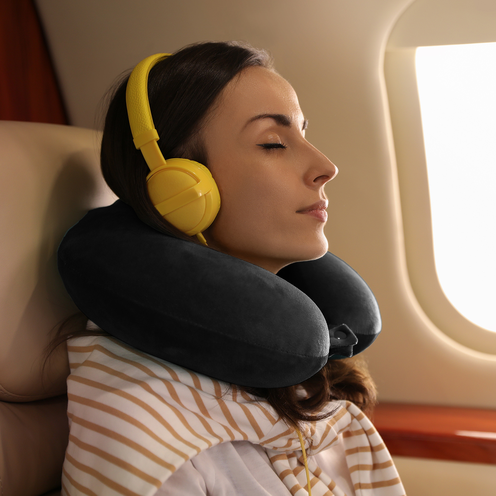 Woman relaxing on plane with headphones and neck pillow