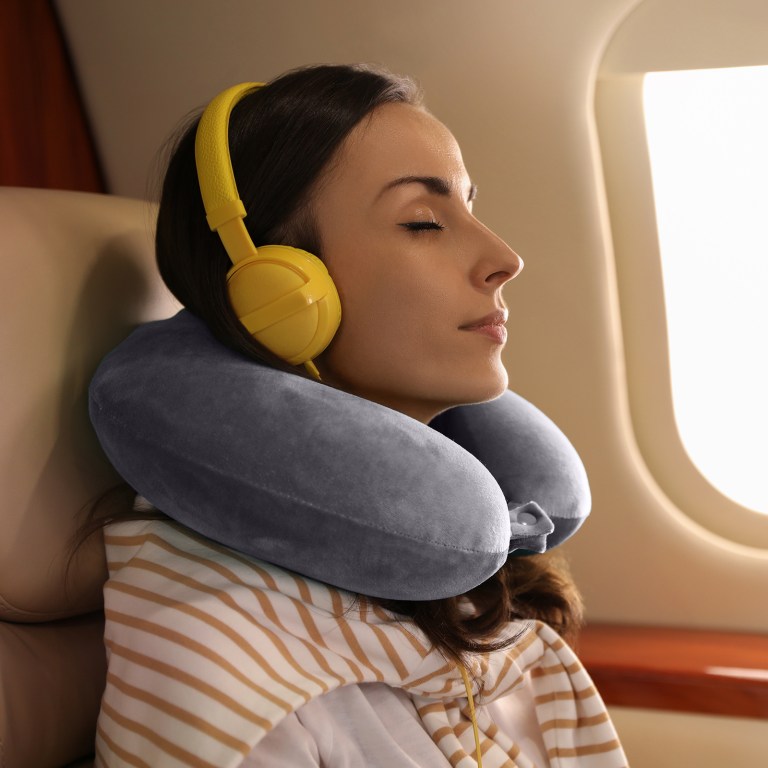 milano decor memory foam travel neck pillow with clip cushion support soft grey Woman relaxing on plane with headphones and neck pillow