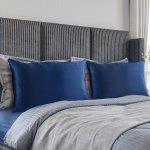 Neatly made bed with blue pillows and striped headboard