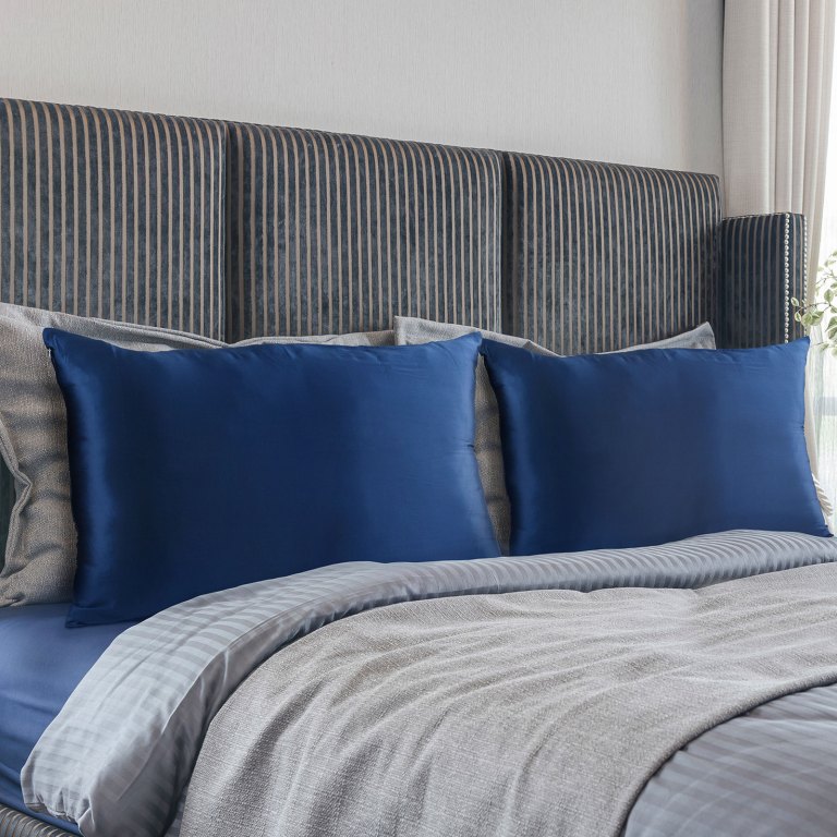 Neatly made bed with blue pillows and striped headboard