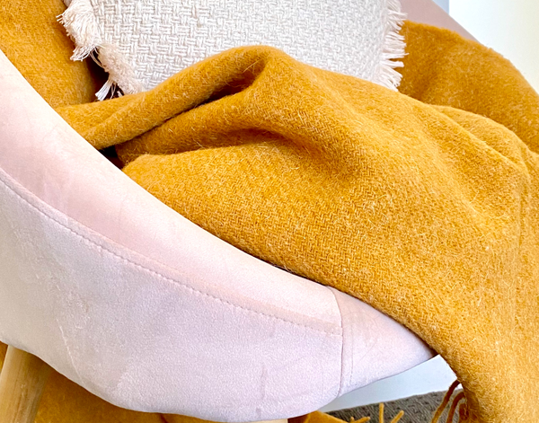 Mustard throw on pink armchair with cushion