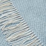 Close-up of blue throw with white fringe
