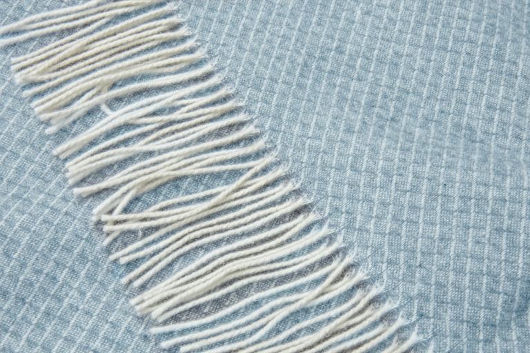 Close-up of blue throw with white fringe