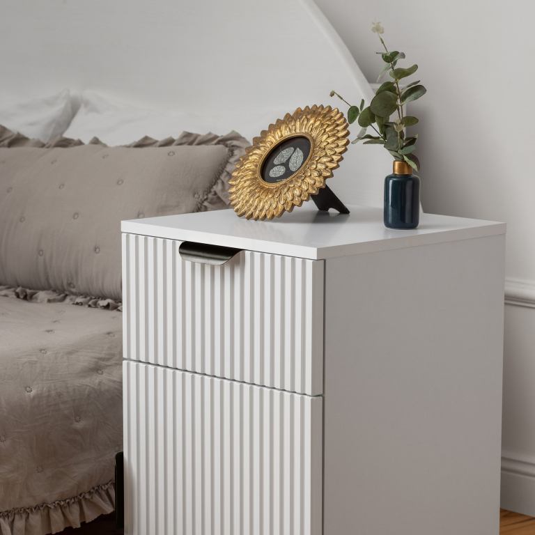 White bedside table with gold frame and vase